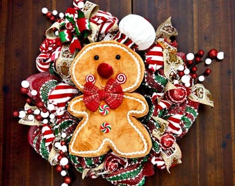 Corona navideña de pan de jengibre: decoración navideña para la puerta con motivos de caramelos de menta, corona de malla roja, verde y blanca con peluche de hombre de jengibre y cintas navideñas.
