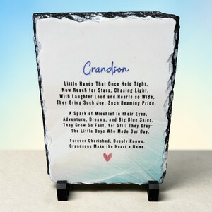 May include: A rectangular slate plaque with a black border and a blue and white background. The text "Grandson" is written in blue script at the top, followed by a poem about grandsons. A small red heart is at the bottom.