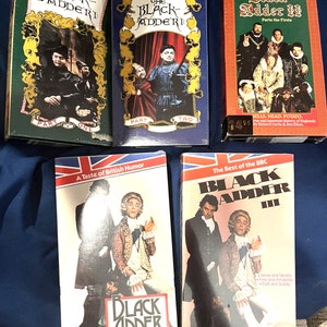May include: A set of six VHS tapes featuring the British comedy series "Blackadder". The tapes are in various colors, including blue, red, and green. The titles of the tapes include "Blackadder", "Blackadder II", and "Blackadder III".