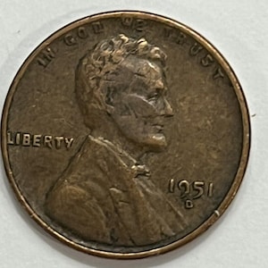 Op de afbeelding: Een koperkleurige Lincoln-cent uit 1951 met de inscripties "In God We Trust" en "Liberty". De munt heeft een portret van Abraham Lincoln op de voorzijde.