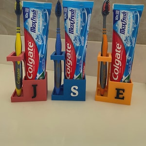 Puede incluir: Tres juegos de cepillos de dientes, pasta de dientes y soportes. Cada juego incluye un tubo de pasta de dientes Colgate Max Fresh y un cepillo de dientes. Los soportes son rojos, azules y naranjas, cada uno con una letra: J, S y E.