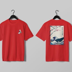 K&ouml;nnte beinhalten: Rotes T-Shirt mit einer kleinen Grafik auf der Vorderseite und einem gro&szlig;en japanischen Wellenmuster auf der R&uuml;ckseite. Das Design auf der R&uuml;ckseite enth&auml;lt Text und ein gerahmtes Bild einer Welle, &Auml;sten und einem Berg.