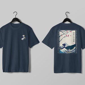 K&ouml;nnte beinhalten: Marineblaue T-Shirts mit japanischer Wellenkunst. Eines hat eine kleine Grafik auf der Vorderseite, das andere ein gr&ouml;&szlig;eres Design auf der R&uuml;ckseite mit dem Text "SCULPTURES REPUBLIC". Das R&uuml;ckendesign enth&auml;lt auch japanischen Text.
