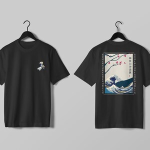 K&ouml;nnte beinhalten: Zwei schwarze T-Shirts mit japanisch inspirierten Designs. Eines hat eine kleine Grafik auf der Vorderseite, das andere ein gr&ouml;&szlig;eres Design auf der R&uuml;ckseite mit einer Welle und Kirschbl&uuml;ten. Der Text "SCULPTURES REPUBLIC" ist vertikal gedruckt.