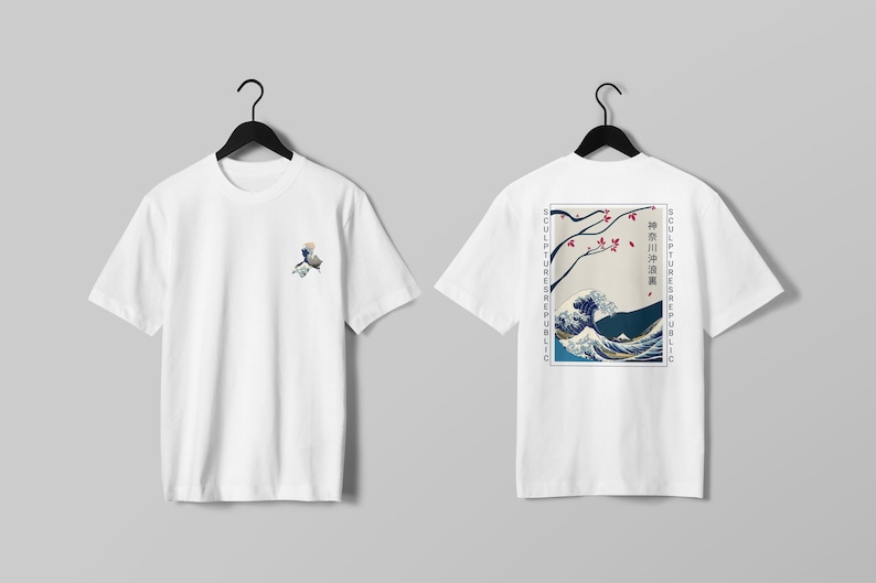 K&ouml;nnte beinhalten: Wei&szlig;e T-Shirts mit japanisch inspirierten Designs. Eines zeigt ein kleines Wellenmuster, das andere einen gr&ouml;&szlig;eren Druck einer Welle, Kirschbl&uuml;ten und Text. Beide Shirts h&auml;ngen an schwarzen Kleiderb&uuml;geln.