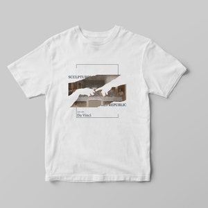 Puede incluir: Camiseta blanca con un estampado gr&aacute;fico de la pintura "La &Uacute;ltima Cena" de Leonardo da Vinci. El gr&aacute;fico est&aacute; parcialmente oscurecido por una silueta blanca de dos manos que se alcanzan mutuamente. El texto "SCULPTURES REPUBLIC" y "Da Vinci" est&aacute; impreso debajo del gr&aacute;fico.