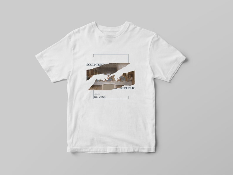 Puede incluir: Camiseta blanca con un estampado gr&aacute;fico de la pintura "La &Uacute;ltima Cena" de Leonardo da Vinci. El gr&aacute;fico est&aacute; parcialmente oscurecido por una silueta blanca de dos manos que se alcanzan mutuamente. El texto "SCULPTURES REPUBLIC" y "Da Vinci" est&aacute; impreso debajo del gr&aacute;fico.
