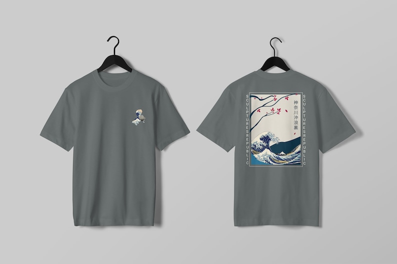 K&ouml;nnte beinhalten: Graues T-Shirt mit einem kleinen Wellenmuster auf der Vorderseite und einem gr&ouml;&szlig;eren japanischen Wellendesign auf der R&uuml;ckseite. Das R&uuml;ckendesign enth&auml;lt japanischen Text und die Worte "SCULPTURES REPUBLIC" vertikal auf beiden Seiten.