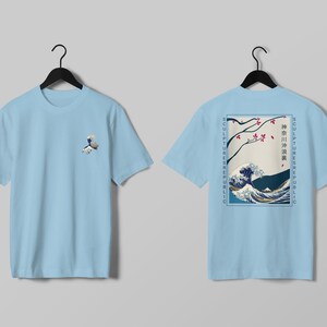 K&ouml;nnte beinhalten: Hellblaue T-Shirts mit japanischem Wellenmuster. Eines zeigt eine kleine Wellengrafik. Das andere zeigt eine gr&ouml;&szlig;ere Wellenszene mit japanischem Text und den Worten "SCULPTURE REPUBLIC" vertikal an den Seiten.