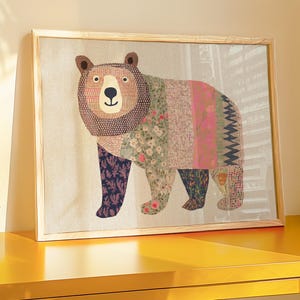 Könnte beinhalten: Ein gerahmtes Kunstwerk eines Bären mit Patchwork-Design in verschiedenen Farben, darunter Rosa, Grün und Lila, steht auf einem gelben Schreibtisch. Eine blaue Lampe mit goldenem Ständer und ein kleiner Holzstuhl sind ebenfalls vorhanden. Eine kleine Topfpflanze sorgt für einen Hauch von Grün.