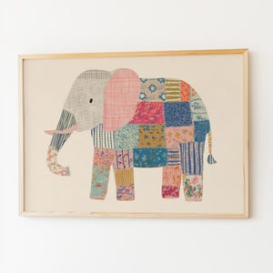 May include: A framed art print featuring a whimsical elephant illustration. The elephant is depicted with a patchwork design in various colors, including pink, blue, and yellow. The background is a neutral beige, and the frame is made of light-colored wood.