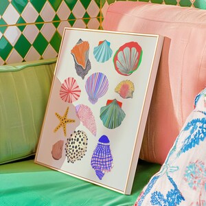 Puede incluir: Una impresi&oacute;n art&iacute;stica enmarcada con ilustraciones coloridas de varias conchas marinas y una estrella de mar. La obra de arte incluye conchas en tonos naranja, azul, rojo, rosa y verde, sobre un fondo crema. El marco es de color dorado claro.