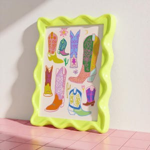 May include: A framed print with a colorful illustration of cowboy boots. The boots are decorated with floral patterns and have different colors, including pink, blue, green, yellow, and orange.