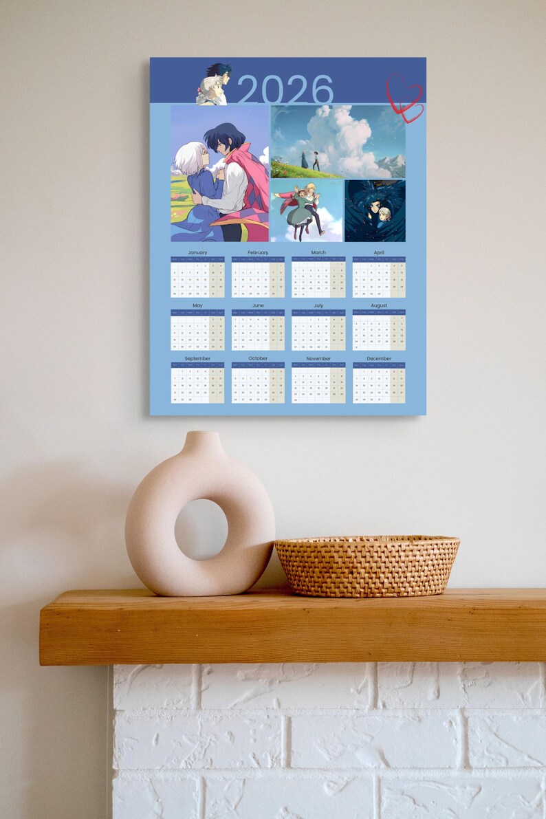May include: A 2026 calendar featuring anime-style illustrations, with a light blue background and monthly date grids. The calendar is displayed on a wall above a wooden shelf with a beige vase and a woven basket.