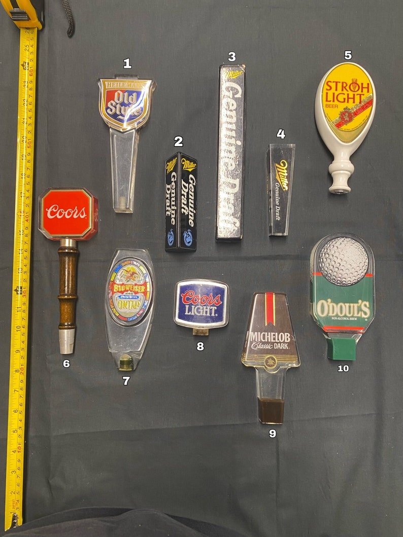Może przedstawiać: Dziesięć r&oacute;żnych uchwyt&oacute;w do kran&oacute;w piwnych, w tym Coors, Budweiser, Miller, Michelob, Old Style, Stroh's Light i O'Doul's. Uchwyty do kran&oacute;w są wykonane z metalu i plastiku i mają r&oacute;żne kolory i wzory.