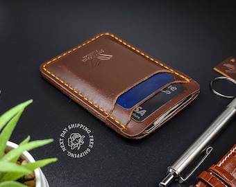 Puede incluir: Una cartera de cuero marrón con detalles de costura amarilla y una ranura para tarjetas. La cartera tiene un logotipo en relieve en la parte delantera y contiene una tarjeta de crédito.