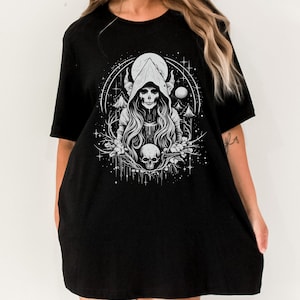 May include: Black oversized t-shirt featuring a white graphic print of a hooded figure with horns, a skull, and a crescent moon.