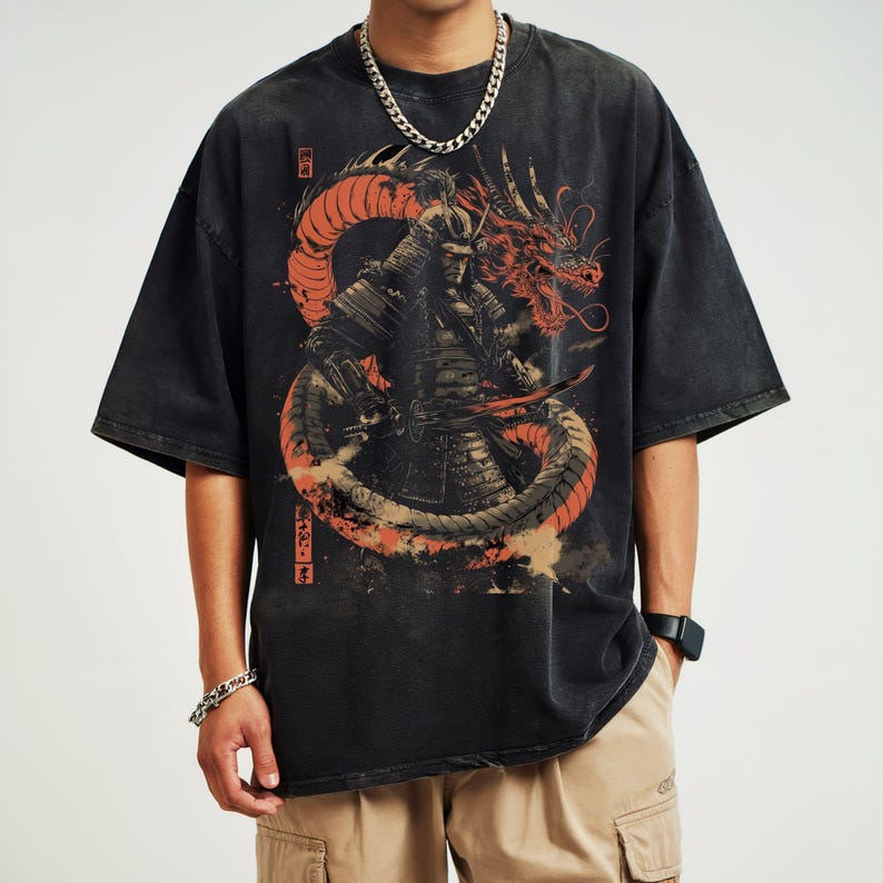 K&ouml;nnte beinhalten: Schwarzes T-Shirt mit einem Grafikdruck eines Samurai-Kriegers, der gegen einen roten Drachen k&auml;mpft. Der Drache ist um den Samurai gewickelt, und das Design ist vor einem schwarzen Hintergrund platziert. Das Shirt hat einen Used-Look.