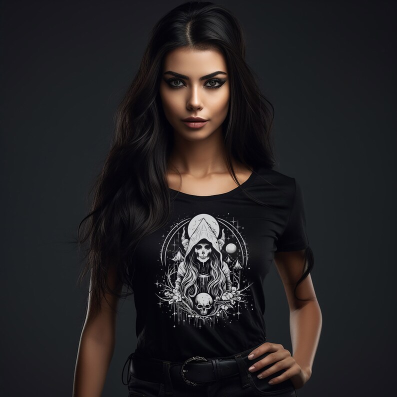May include: A woman with long black hair is wearing a black t-shirt with a white graphic print of a hooded figure with a skull face. The graphic also includes a crescent moon, stars, and a skull.
