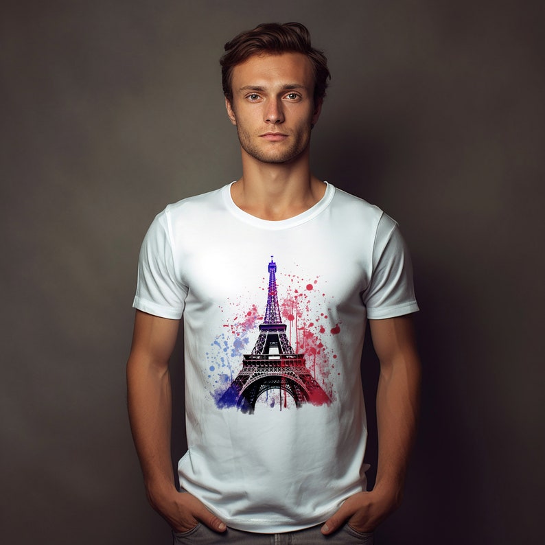 Op de afbeelding: Wit T-shirt met een afbeelding van de Eiffeltoren in zwart-wit met blauwe en rode waterverf spatten.