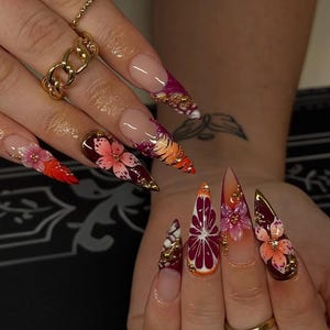 Tropische hibiscus 3D-bloem op de nagels | Gouden chromen accenten zonsondergang ombre | Lange stiletto nagelkunst in maximalistische stijl | Luxe handgeschilderde set