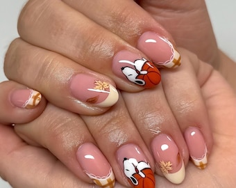 Puede incluir: Arte de uñas con base nude y puntas francesas en patrón de cuadros blanco y naranja. El diseño incluye ilustraciones pintadas a mano de un perro blanco con orejas negras abrazando una calabaza naranja y un pequeño pájaro amarillo.