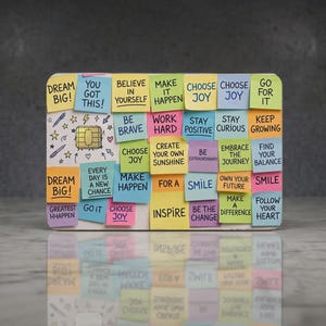 May include: A rectangular credit card featuring a collage of colorful sticky notes with motivational phrases like Dream Big, Choose Joy, and Make It Happen. A gold EMV chip is centered on the left side, surrounded by small hand-drawn star and pen icons.