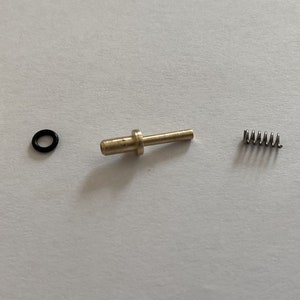 May include: Five brass parts for a gas-powered device, including a threaded connector, a spring, a pin with a washer, and two small threaded caps.