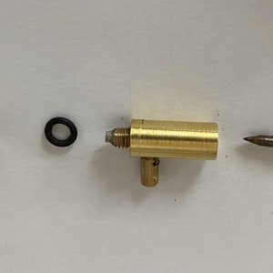 May include: Three brass fittings with a black o-ring. The fittings have a threaded end and a side outlet. The third fitting is a metal rod with a pointed end.