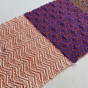 Puede incluir: Un tapiz tejido con cuatro patrones diferentes en naranja, blanco, morado y gris.