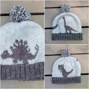 Puede incluir: Tres gorros de punto grises con pompones. Cada gorro presenta una silueta de dinosaurio diferente en negro.