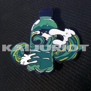 May include: A green and blue enamel pin in the shape of a water bottle with a wave design. The pin has a dark blue cap and the text "KAIJURIOT" in white.