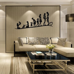 Puede incluir: Un vinilo decorativo de pared con silueta negra que representa a una familia que avanza por una línea curva. Las figuras incluyen una madre con un bebé, un niño y niños mayores. El vinilo está montado en una pared beige sobre un sofá color crema.