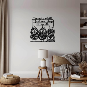Puede incluir: Arte de pared de metal negro con tres búhos de ojos grandes y un letrero que dice "I'm not a misfit, I just see things differently." Los búhos están posados en una línea, creando una pieza decorativa.