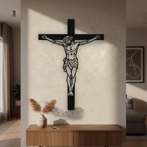 Puede incluir: Una pieza de arte mural de metal negro que representa un crucifijo con la silueta detallada de Jesús con una corona de espinas. La figura está centrada en una cruz, con líneas limpias y un acabado plano y mate.