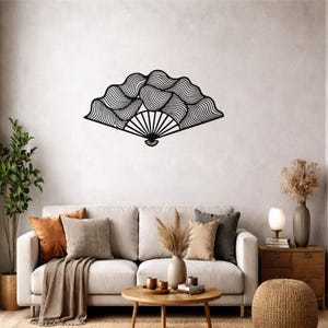 Puede incluir: Un abanico decorativo de pared en color negro que presenta una serie de líneas curvas y onduladas que irradian desde un punto central. El diseño consiste en un marco sólido con patrones fluidos que crean movimiento y profundidad.