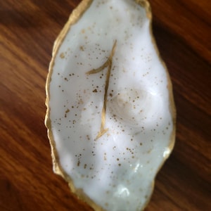 May include: White oyster shell with gold accents and the number "1" painted on it.