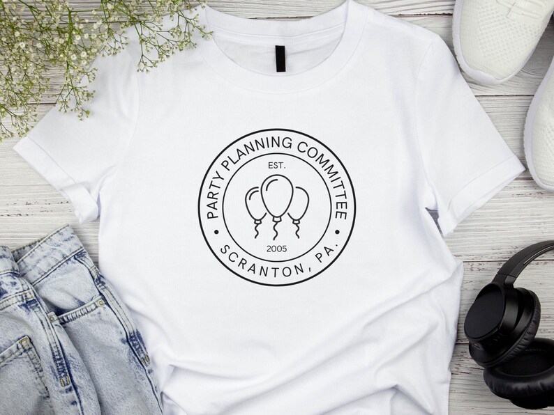May include: White t-shirt with a black and white logo that says "Party Planning Committee, Est. 2005, Scranton, PA". The logo features three balloons.