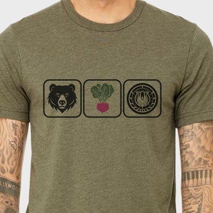 May include: A green t-shirt with a black bear, a beet, and a black and white logo with a bird inside a circle.