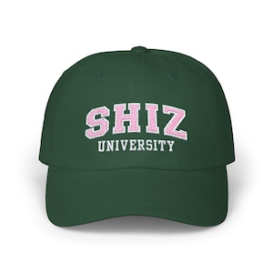 Puede incluir: Una gorra de béisbol verde oscuro con un logotipo bordado en rosa que dice "SHIZ UNIVERSITY" en letras blancas.
