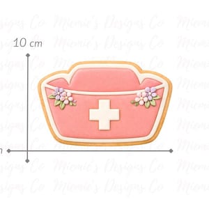 Peut inclure: Emporte-pièce en forme de chapeau d'infirmière rose, 10 cm de large et 7 cm de haut, avec une croix blanche et des motifs floraux. Le découpoir a un contour marron clair. Le texte "Miemie's Designs Co" est inclus.
