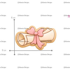 May include: A cookie cutter in the shape of a scroll with a pink bow, ideal for graduation treats. The scroll measures 9 cm long and 6 cm high. The product code is MDC 033.