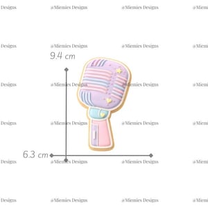 Pode incluir: Um biscoito em forma de microfone em cores pastel, com 9,4 cm de altura e 6,3 cm de largura, com um corpo lilás claro e detalhes listrados. O design inclui pequenas estrelas e corações. O texto "MDC 189" é visível.
