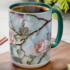 May include: A ceramic mug with a floral design, filled with a dark liquid. The mug features a green handle and rim, with a design of pink flowers and gold accents. The text "Printed Mug" and "HappyWKNDClub" are at the bottom.