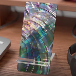 Könnte beinhalten: Ein flach bedruckter Handy-Display-Ständer mit einem schillernden Design in Grün-, Lila- und Blautönen. Der Ständer besteht aus transparentem Material. Der Text "Flat Printed Mobile Display Stand" ist unten.
