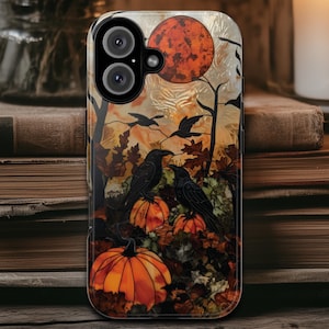 May include: A phone case featuring a Halloween-themed design. The case displays a full moon, crows, pumpkins, and autumn leaves in shades of orange, black, and brown. The case is on a wooden surface with books and a candle in the background.