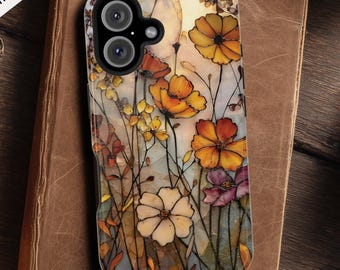 May include: A floral phone case with a watercolor design featuring orange, yellow, and purple flowers. The case is compatible with MagSafe and rests on a vintage book. The case has a dual-lens camera cutout.