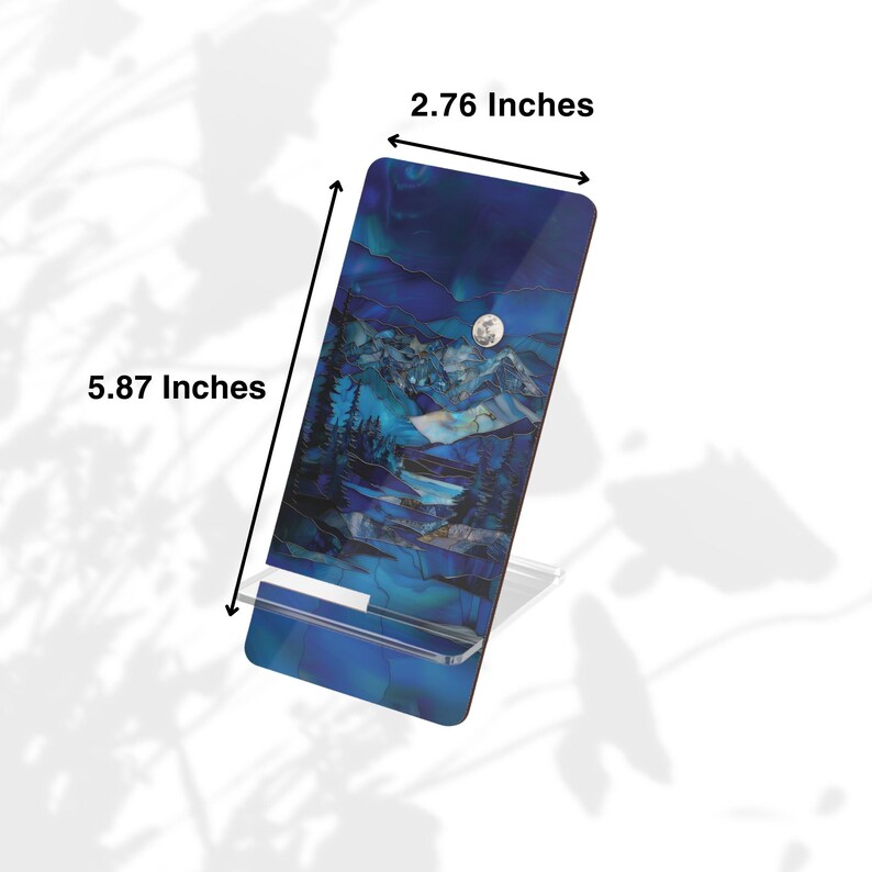 May include: A rectangular phone stand with a blue and white mountain landscape design. The stand is 5.87 inches tall and 2.76 inches wide. The stand is made of a clear material and is designed to hold a phone or tablet.