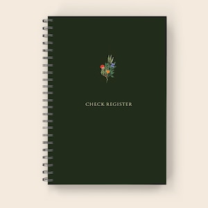 May include: A dark green spiral bound notebook with the text "CHECK REGISTER" in gold lettering. A small floral illustration with orange, red, blue, and green flowers is in the top center of the cover.