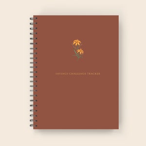May include: A brown spiral bound notebook with the text "SAVINGS CHALLENGE TRACKER" and a small illustration of yellow flowers.